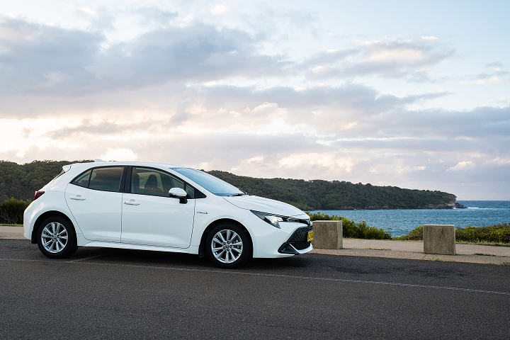 White hatchback car with a beach on the background